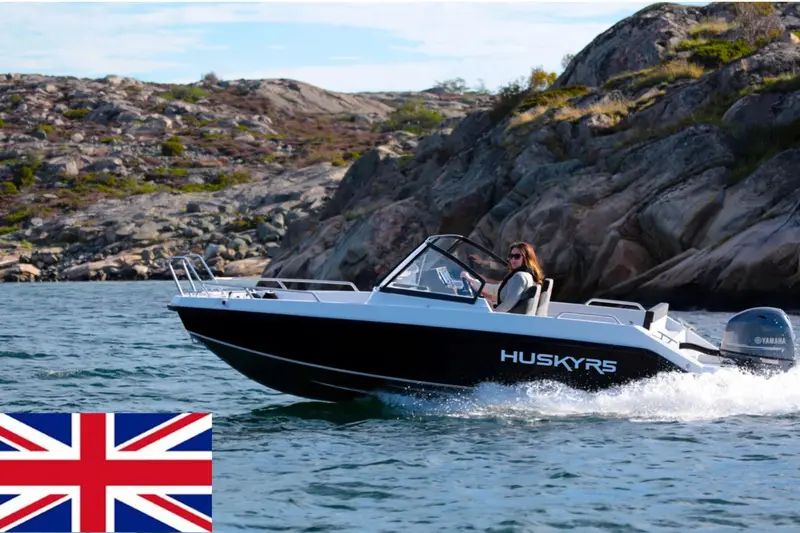 En motorbåt i fart ved svaberg, med det britiske flagget i hjørnet