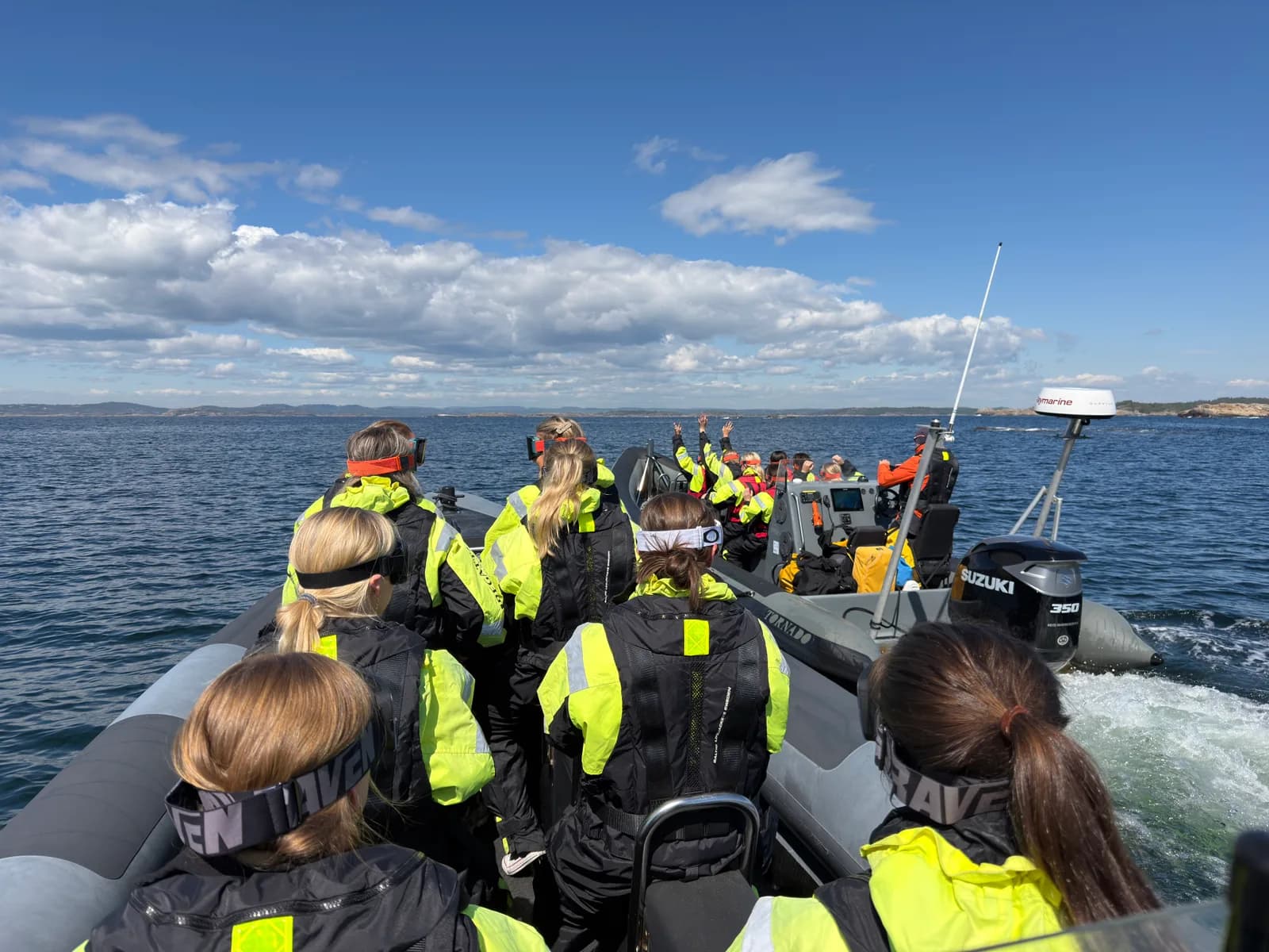 Gjester i flytedrakter om bord i en RIB på fjorden