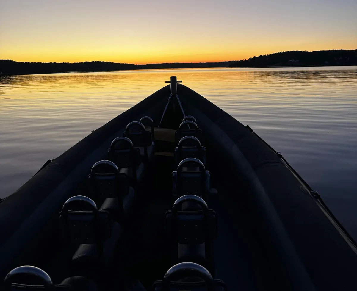 Baugen på en RIB i solnedgang, stille gyllent vann